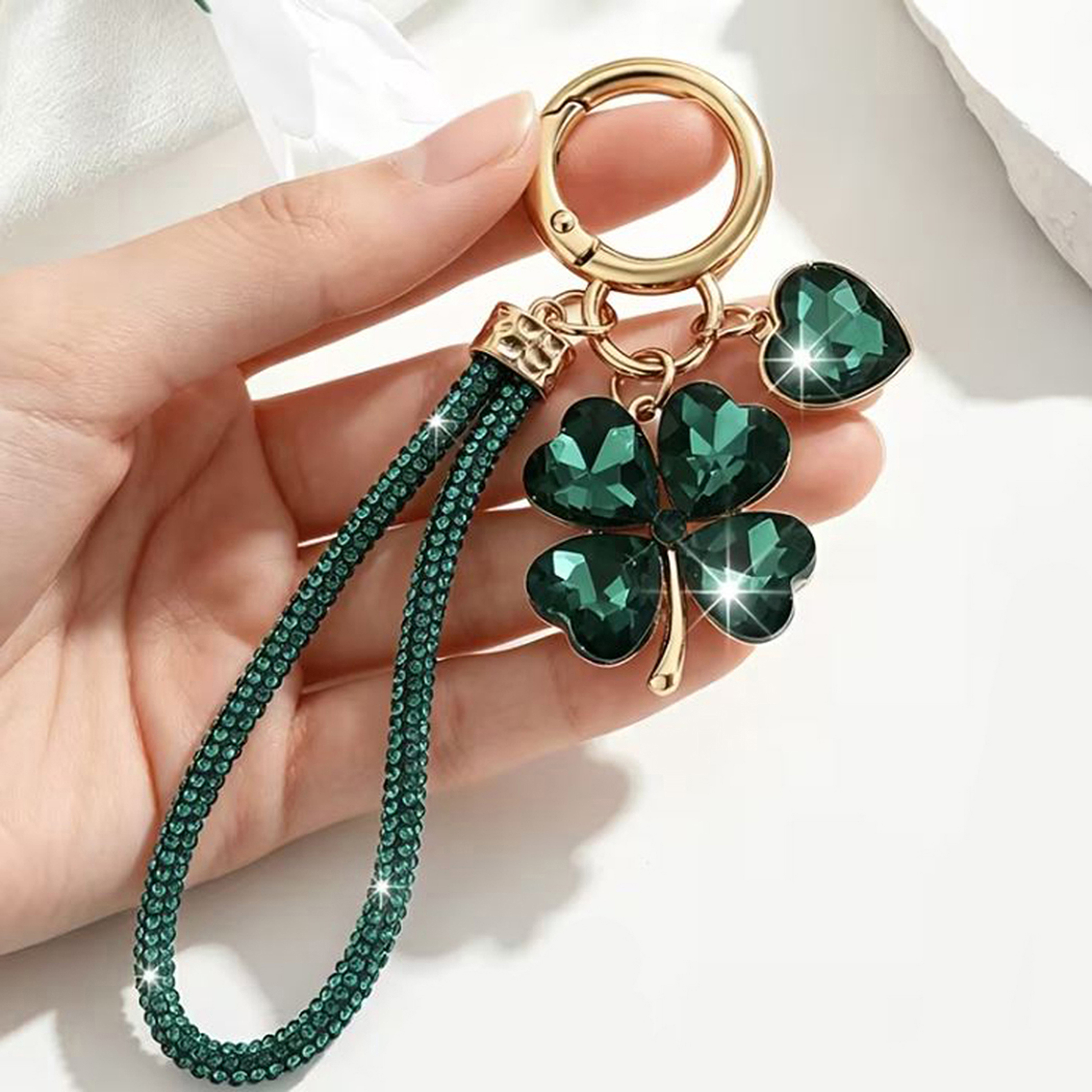 Emerald green crystal four leaf clover keychain bag charm held in hand showing sparkle detail