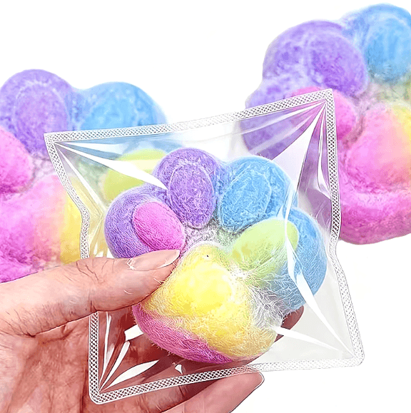 Close-up of rainbow cat paw squishy fidget toy in packaging held in hand